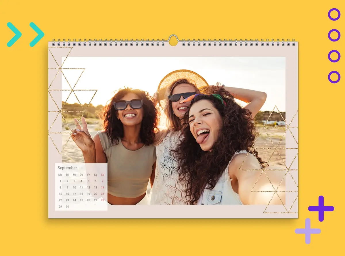 Wandkalender A4 quer mit einem Fotomotiv von drei Freundinnen, die in sommerlicher Kulisse ein Selfie machen. Der Kalender liegt auf einem gelben Hintergrund.